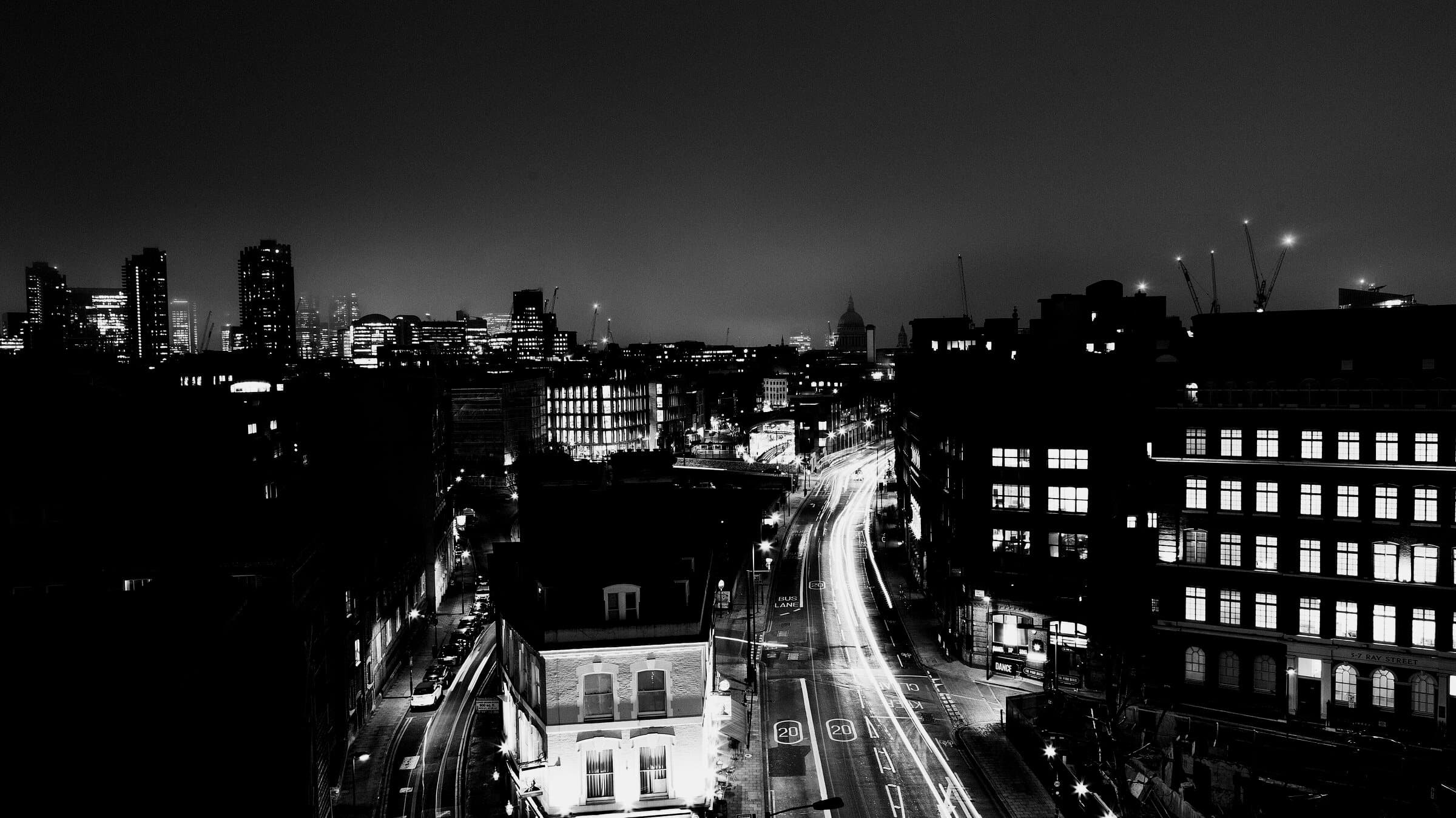 Cruce urbano de noche visto desde altura con estelas de faros