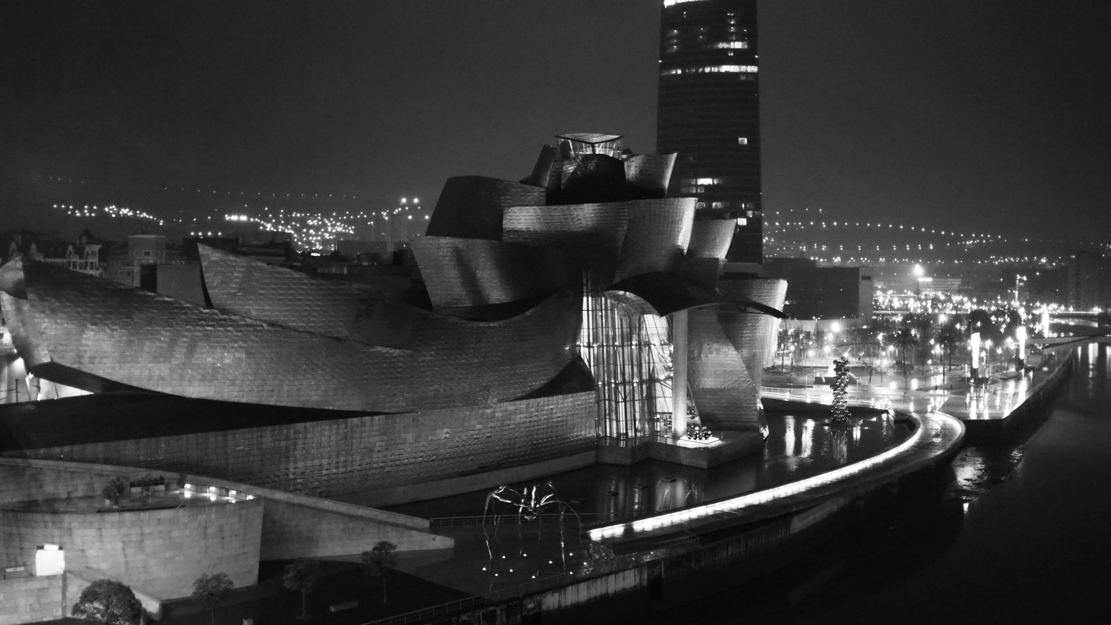 El Museo Guggenheim y la Torre Iberdrola iluminados de noche junto a la ría de Bilbao