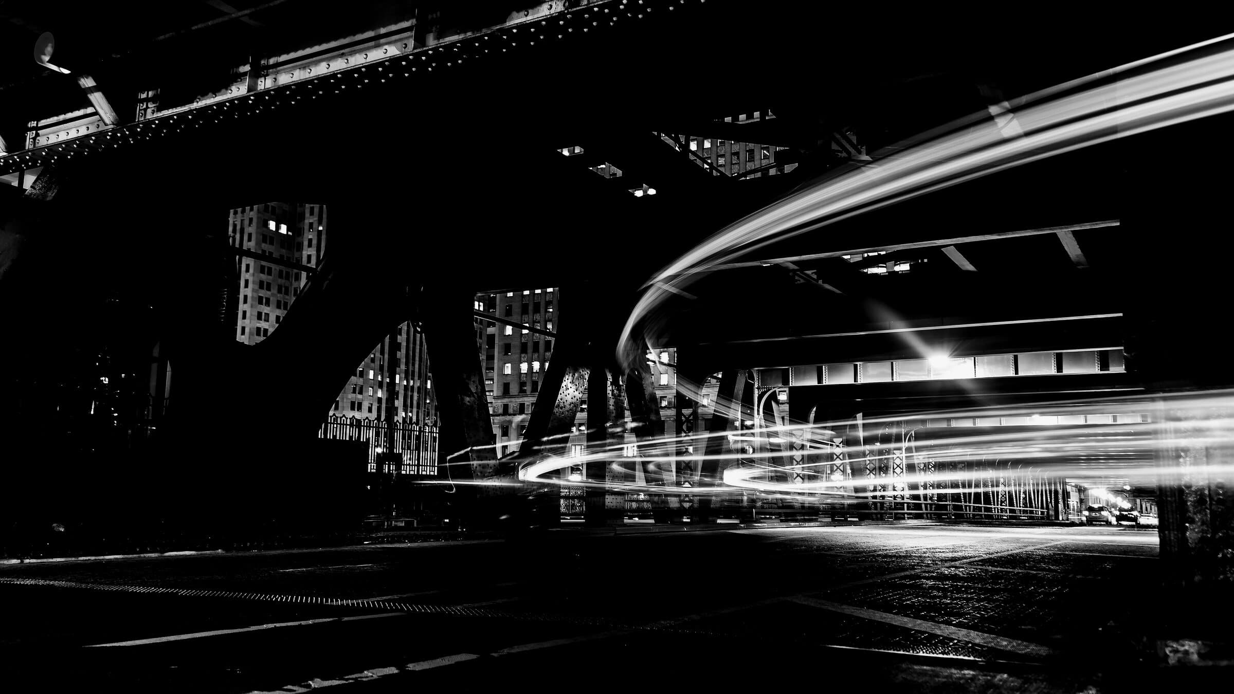 Estelas de luz de vehículos bajo un paso elevado urbano